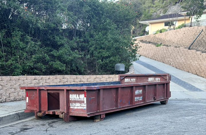 Roll-off dumpster placed against a retaining wall at a Los Angeles commercial property