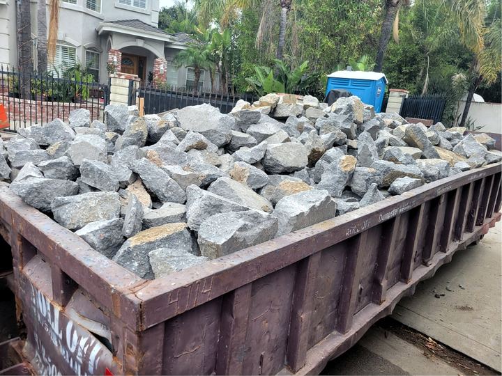 Lowboy roll-off dumpster filled with broken concrete and rock in Los Angeles