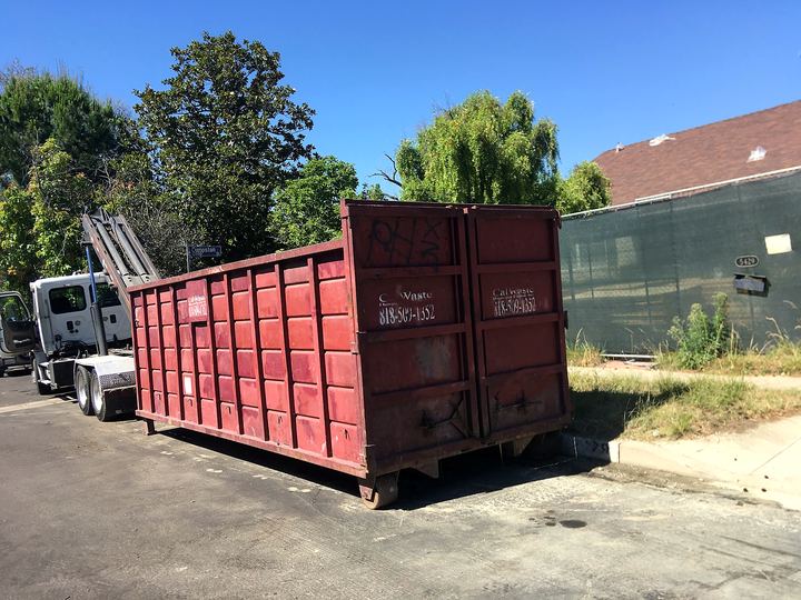 Construction roll-off dumpster positioned alongside a building on a Los Angeles job site