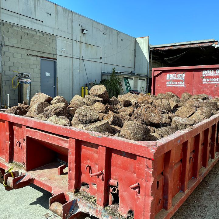 Roll-off dumpster filled with boulders and dirt from a Los Angeles landscaping job
