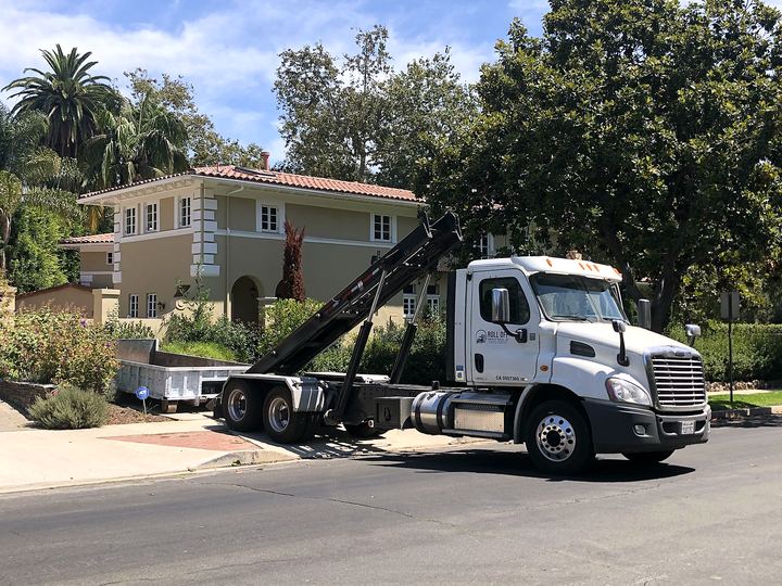 Roll-off dumpster truck delivering to a hillside residential home in Los Angeles