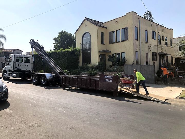 Roll Off Dumpster Rental truck delivering a dumpster outside a Spanish-style Los Angeles home