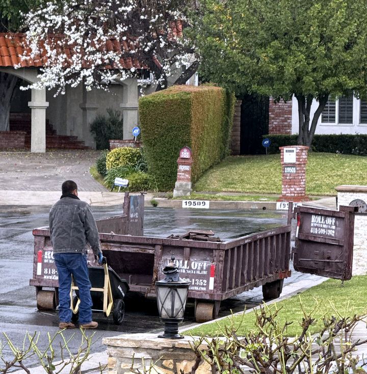 Low-profile roll-off dumpster placed on a residential driveway during a cleanout