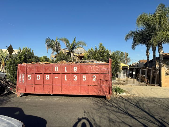 Roll Off Dumpster Rental red bin with phone number on a palm-lined Los Angeles street
