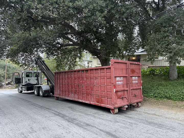 Red 40-yard roll-off dumpster delivered on a tree-lined residential street in Los Angeles